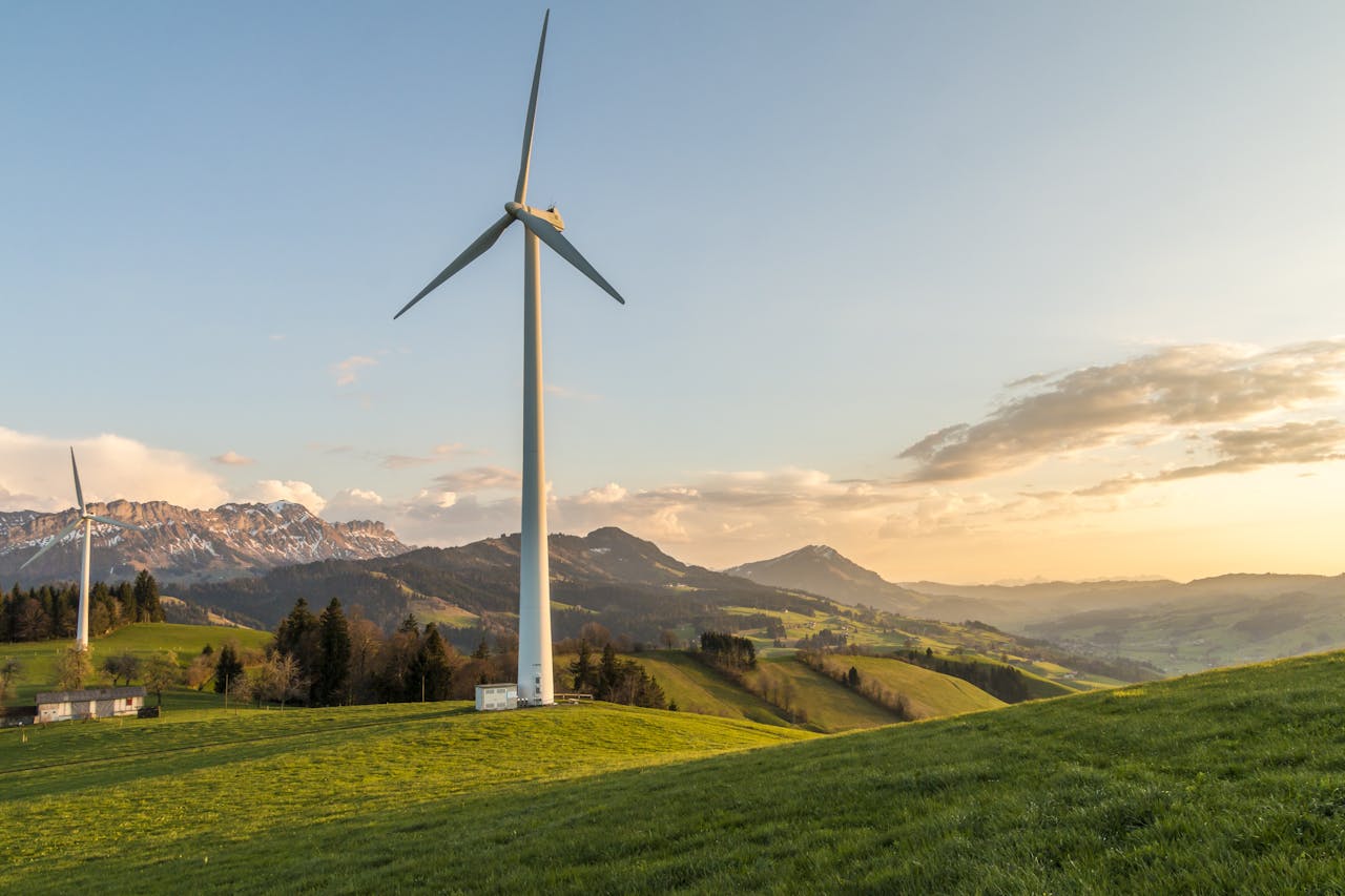 Peaceful countryside with wind turbines during sunset, showcasing sustainable energy.