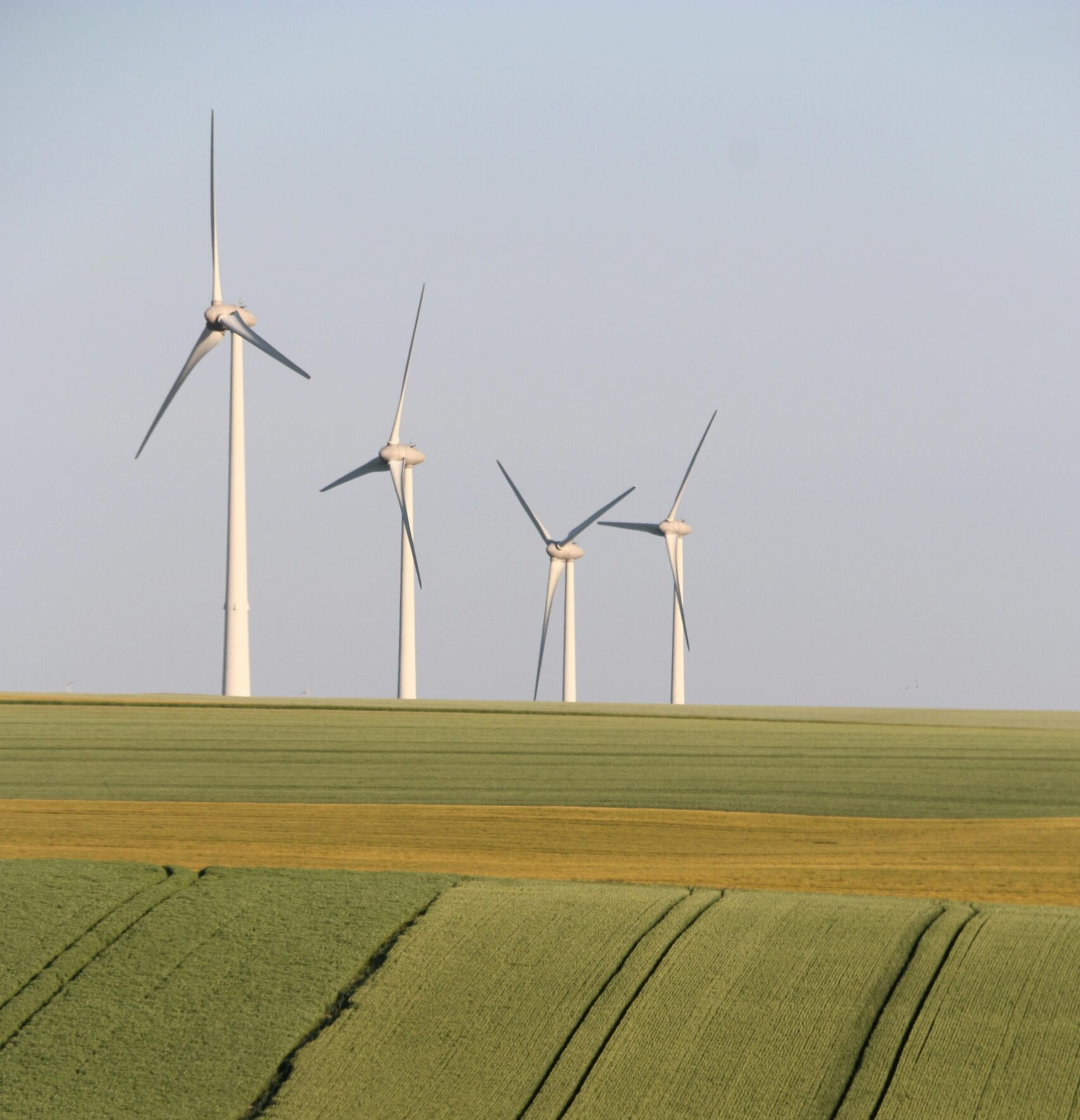 Wind turbines in the countryside generate eco-friendly energy amid vast fields.